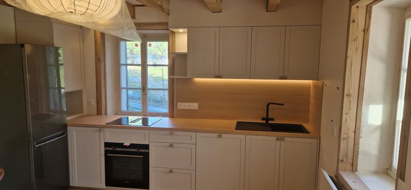 Cuisine blanche à façades encadrées, plan de travail et crédence décor chêne, éclairage sous les meubles hauts