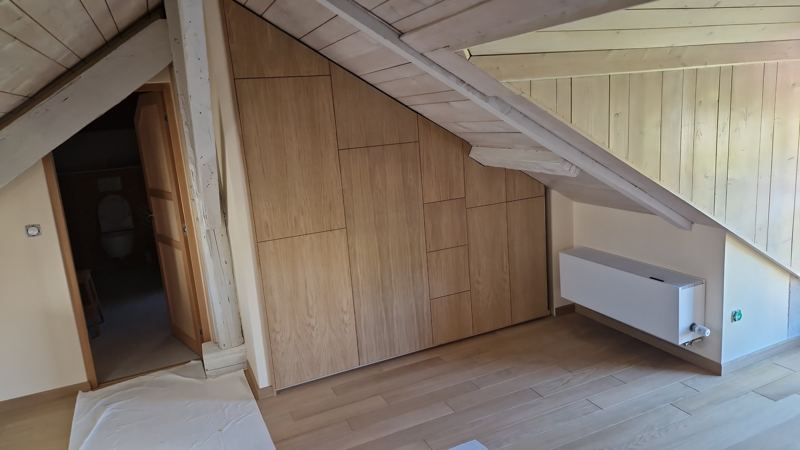 Mur de rangements sous pente, façades en chêne clair à joints creux qui suivent le rampant
